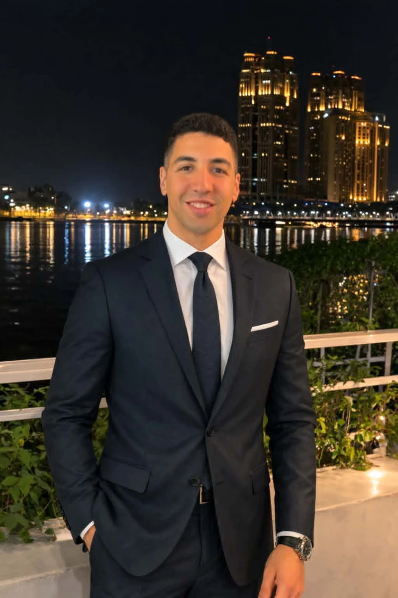 Ahmed Alwakil wearing a dark suit beside the waterfront at night